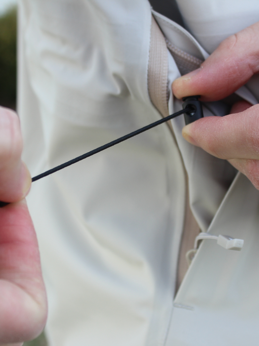 Close-up of a person adjusting a button on a beige suit jacket.

