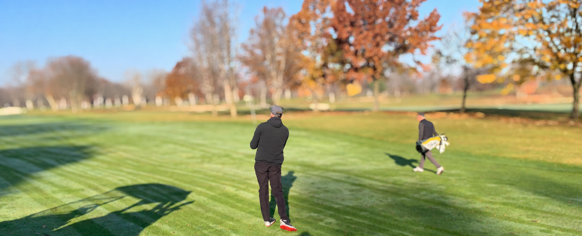 Golfer in a Tullycross hoodie and Nimmo vest walking a fall fairway