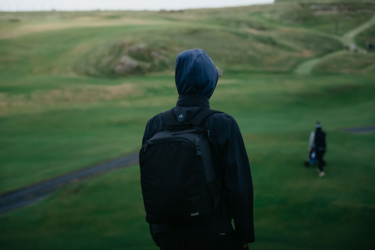 Golfer in rain gear overlooking a coastal links course